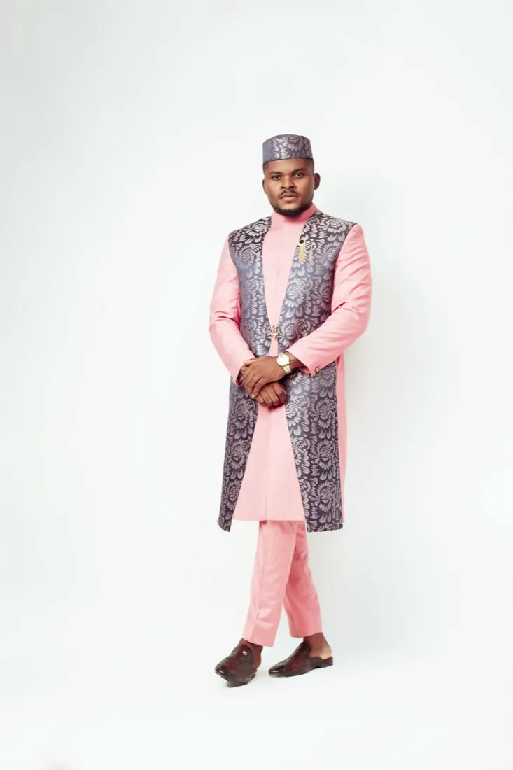 Full-length portrait in a pink and silver brocade agbada