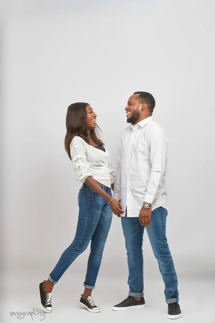 Couple holding hands and laughing, full length on white