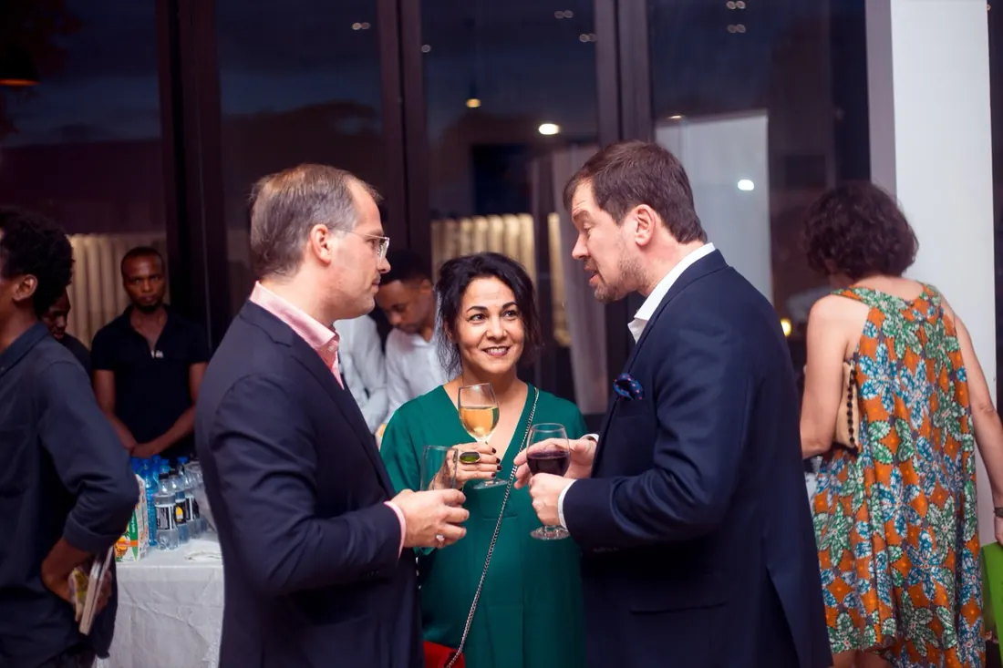 Three guests mid-conversation with drinks at an evening reception