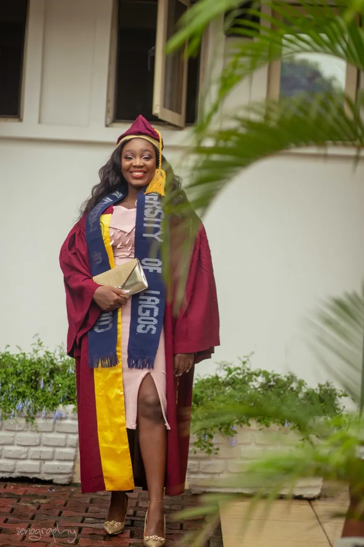 Graduate in gown and sash framed by palm leaves