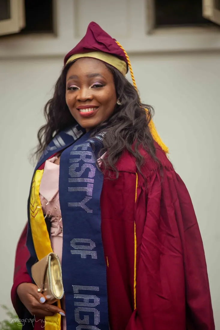 Graduate looking back over her shoulder in gown and university sash