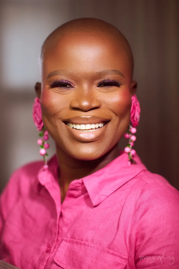 Close portrait, shaved head, pink shirt and floral earrings
